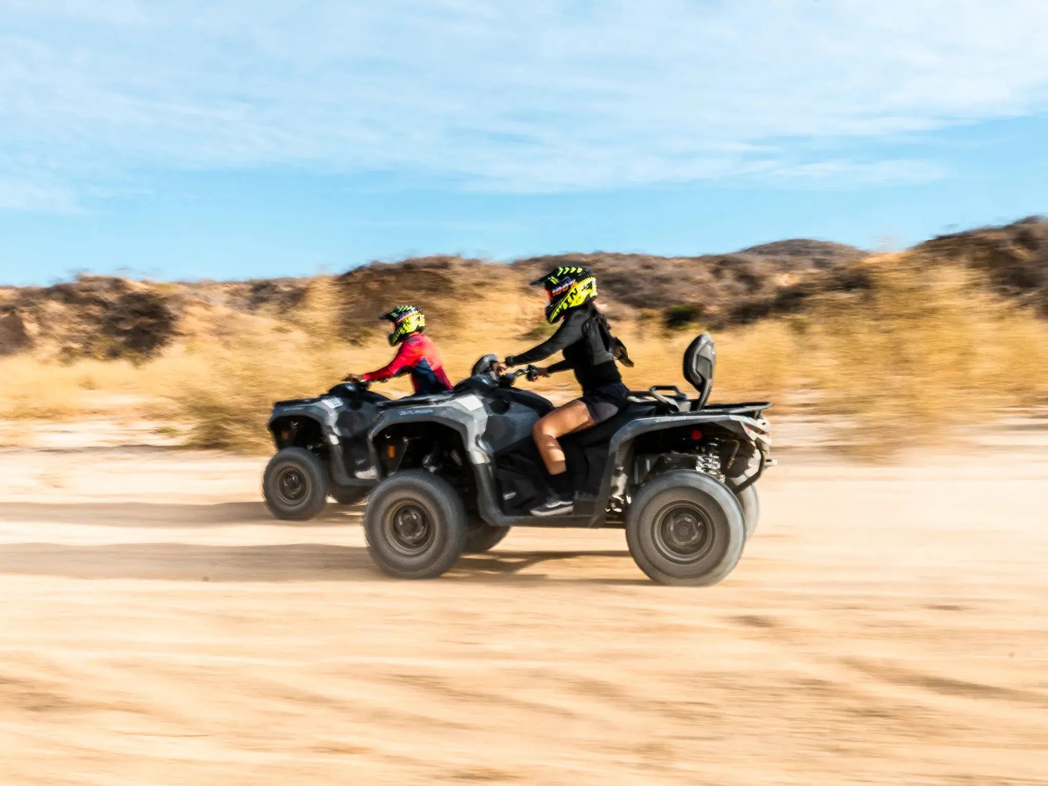 Two ATVs racing across the desert kicking up dust at Wild Canyon Adventures in Los Cabos