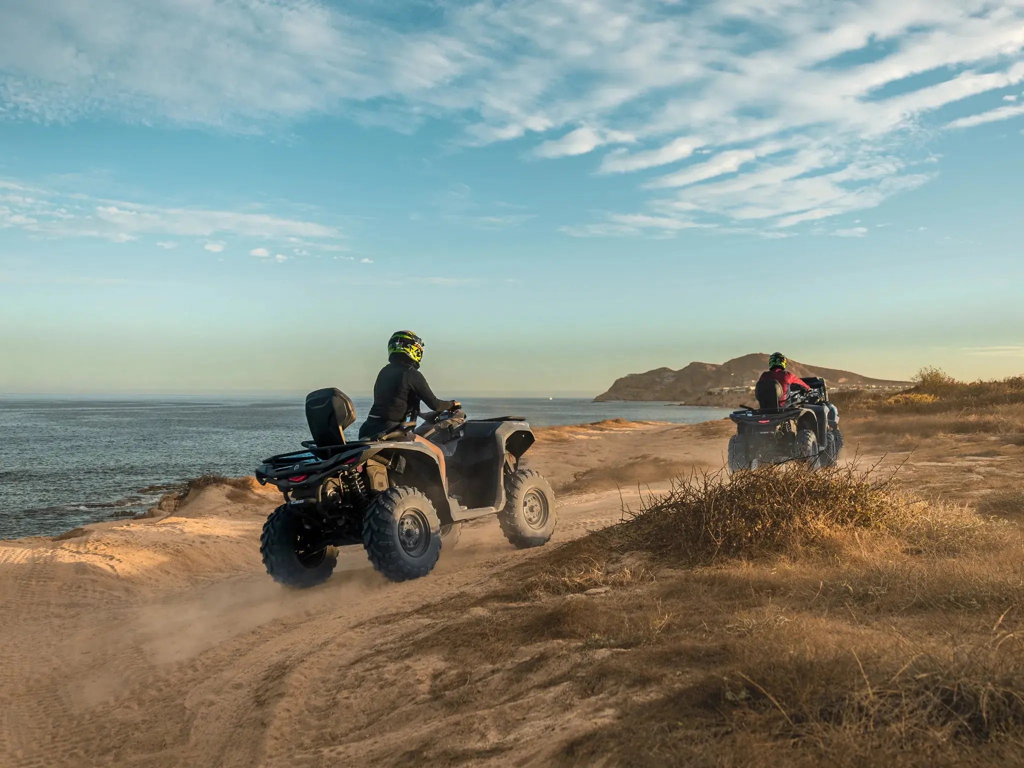 Two ATVs at a clifftop overlook above the sea at sunset during a Wild Canyon Adventures tour in Los Cabos