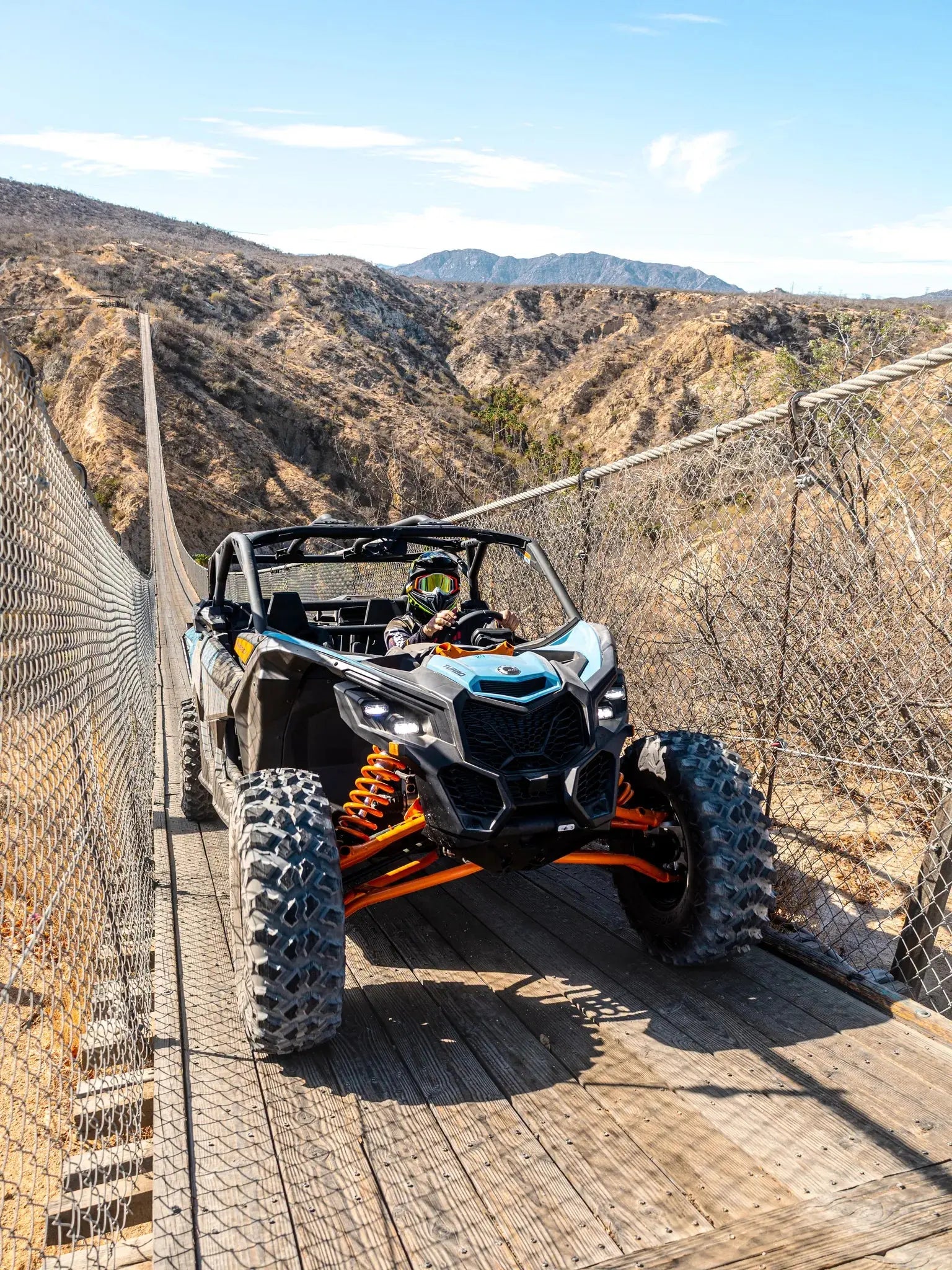 Can-Am Maverick UTV on the Wild Canyon suspension bridge with desert mountains behind in Los Cabos