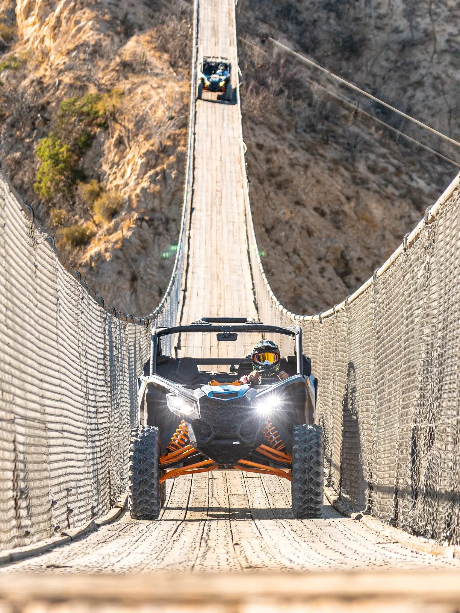 Two Can-Am Maverick UTVs crossing the Wild Canyon suspension bridge above a canyon in Los Cabos
