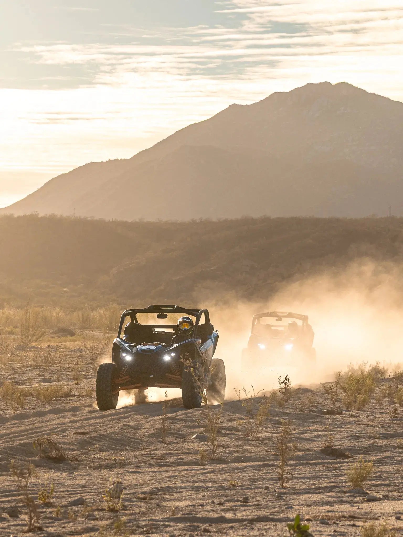 Two Can-Am Maverick UTVs driving toward the sunset with desert mountains at Wild Canyon Adventures, Los Cabos