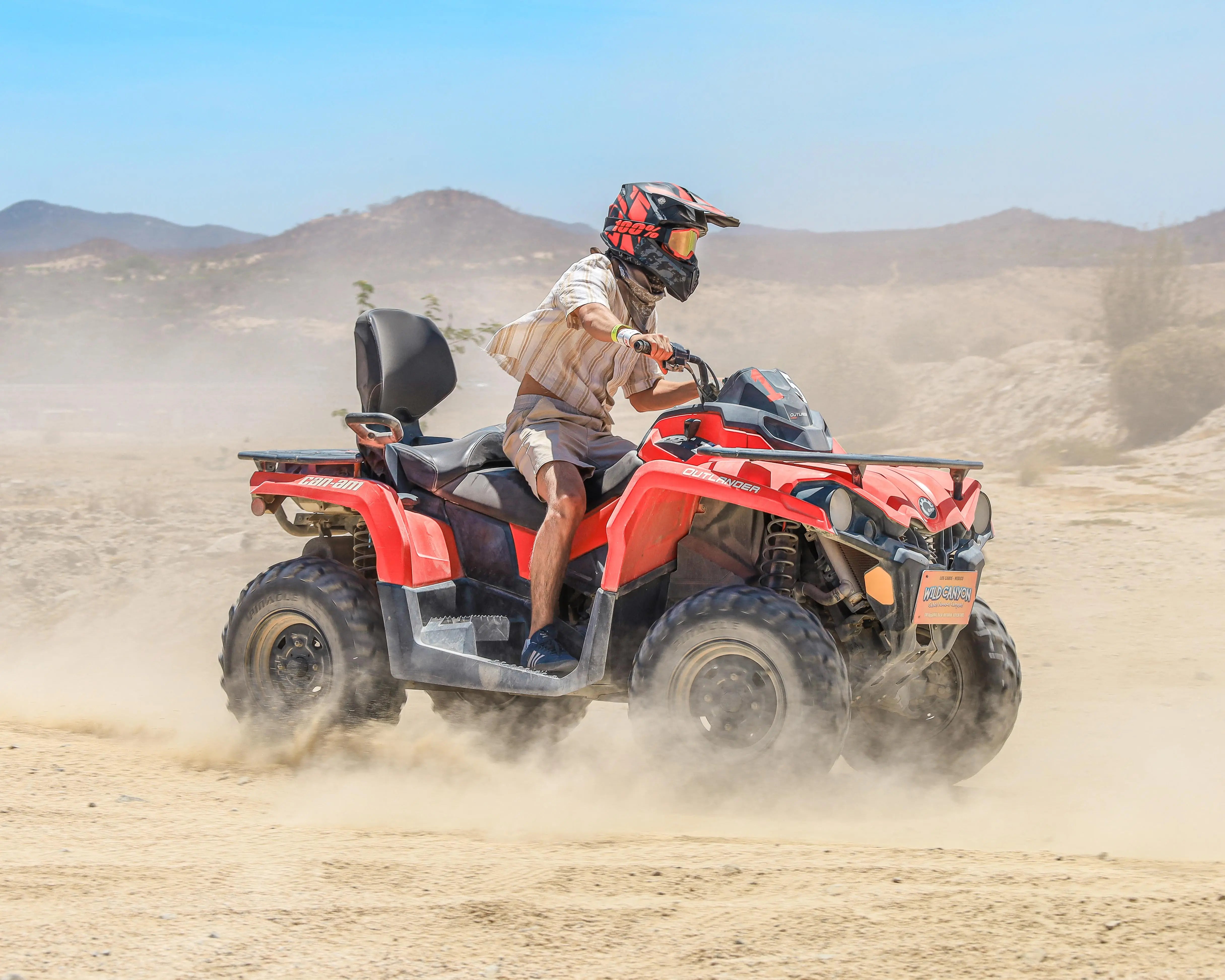 ATV rider kicking up dust on Wild Canyon's exclusive desert trails in Cabo San Lucas with mountain backdrop