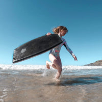 Girl running on the beach carrying a boogie board