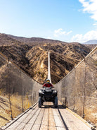 ATV crossing the Wild Canyon suspension bridge framed by Baja desert mountains in Los Cabos
