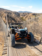 Can-Am Maverick UTV on the Wild Canyon suspension bridge with desert mountains behind in Los Cabos