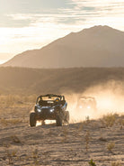 Two Can-Am Maverick UTVs driving toward the sunset with desert mountains at Wild Canyon Adventures, Los Cabos