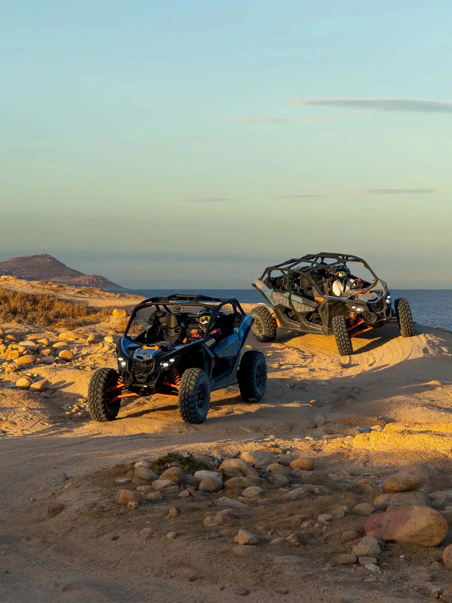 Two Can-Am Maverick UTVs on a coastal bluff overlooking the sea at golden hour, Wild Canyon Adventures, Los Cabos