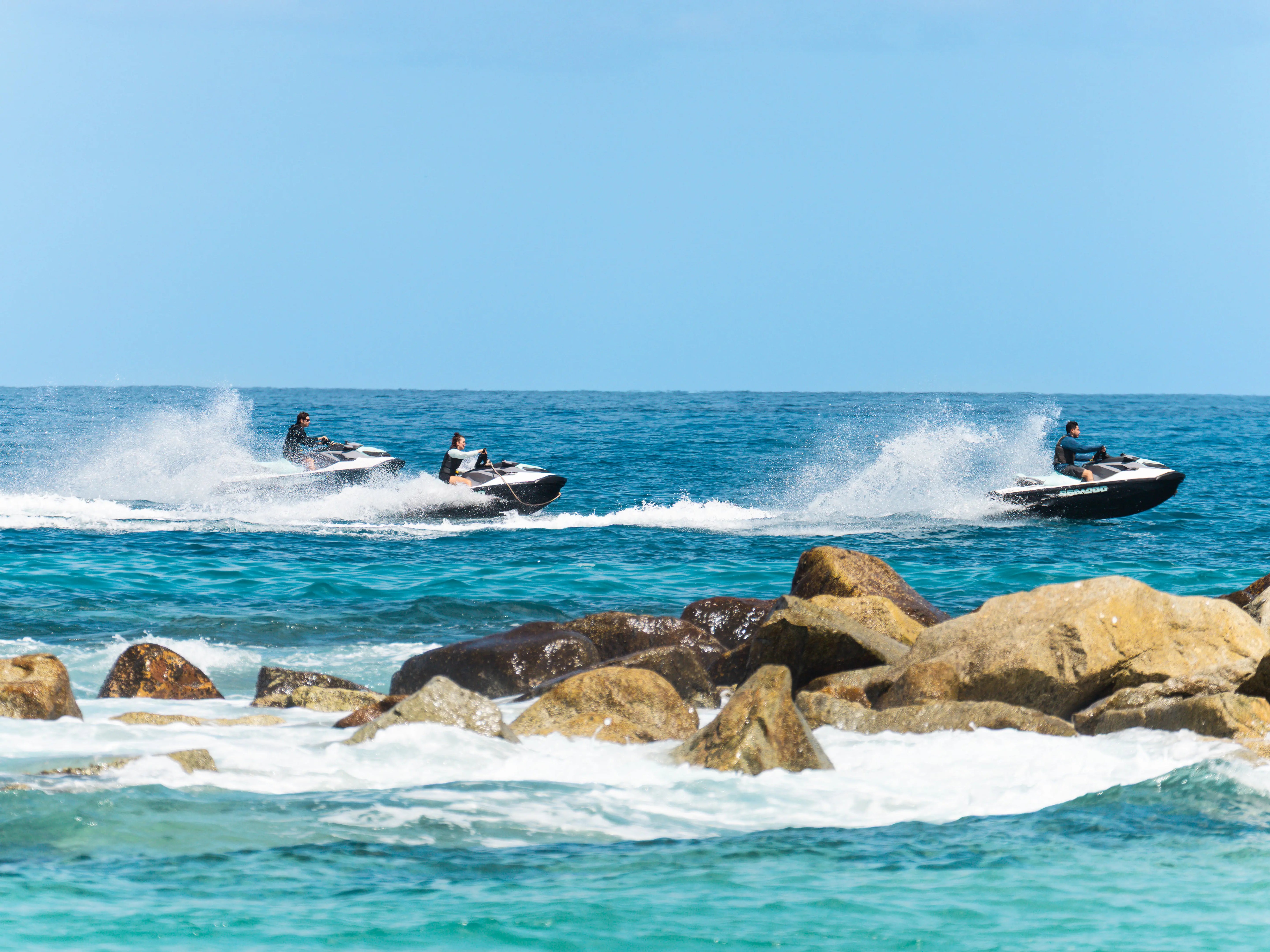Couple waving while riding a Sea-Doo GTX jet ski off the Los Cabos coast with Wild Canyon Adventures