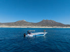 Expedition boat anchored by a mountainous Baja shoreline on a shore fishing trip